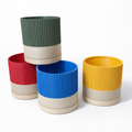 Set of colorful cylindrical planters with ribbed texture on a white background